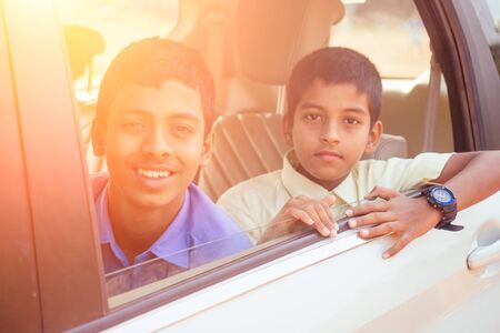 two indian boys ready to go to school on the carの写真素材