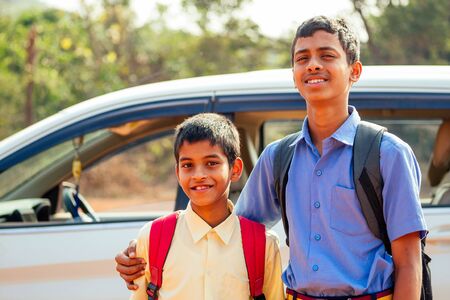 two indian boys ready to go to school on the carの写真素材