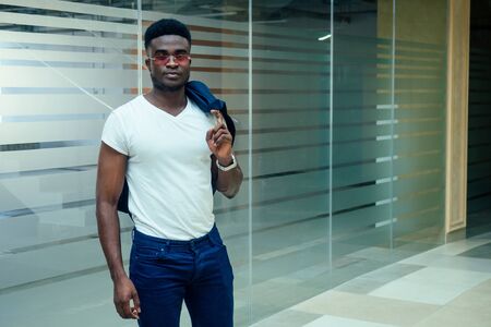 african american man holding big smartphone and posing in shoping mall hall