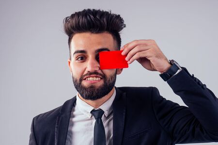 indian young handsome black hair man in stylish business suit holding credit card in studio isolate white background.contactless payment conceptの写真素材