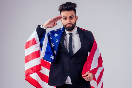 arabian young handsome black hair man in stylish business suit holding american flag in studio isolate white background.Independence Day conceptの写真素材