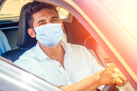 Indian businessman in car outdoors on sea beach summer good day.a man in a white shirt and mask...