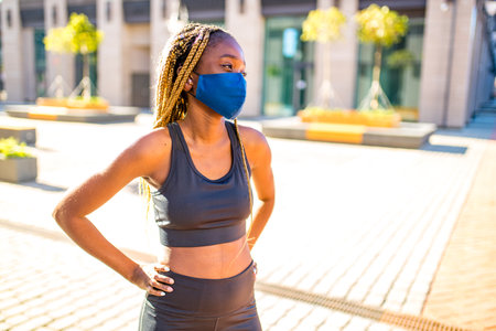 african american woman with long yellow dreadlocks pigtails working out outdoors with mask in down townの写真素材