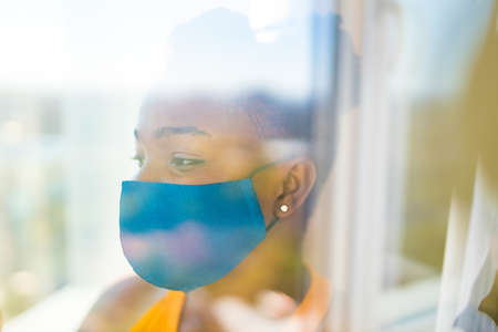 african american woman feeling alone at her home looking to outdoors from her apartment balcony