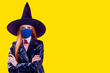 redhaired ginger woman wearing black leather jacket for halloween party ,studio yellow background.