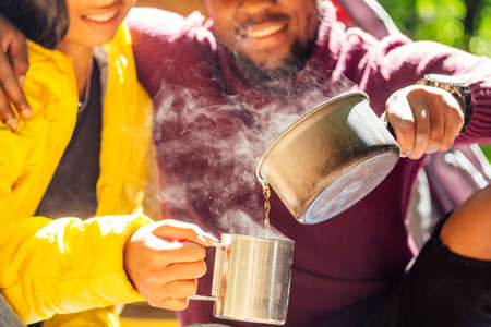 african american man in yellow jacket taking a rest in forest with coffee