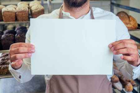man holding template banner poster mockup in bakery vacancyの写真素材