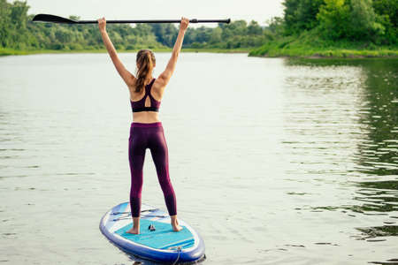 woman on sup sup board in nature at evening