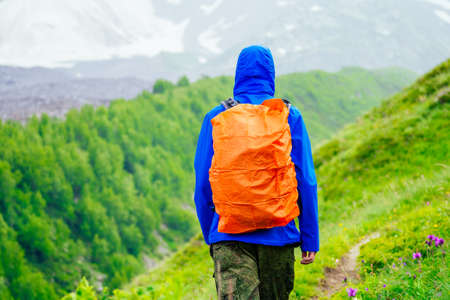 man in blue jacket with rain in mountains