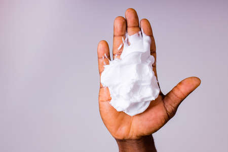 African man holds and show a piece of wet soap in studio white backgroundの写真素材