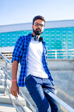 arabian young man in stylish checkered shirt and white t-shirt in downtown at summer day