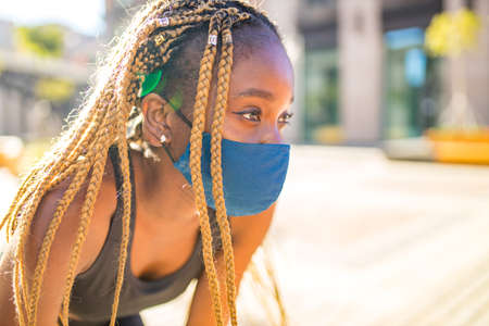 african american woman with long yellow dreadlocks pigtails working out outdoors with mask in down townの写真素材