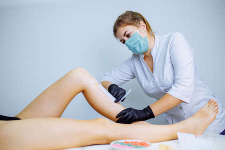 Sugaring: woman at cosmetics salon waxing legsの写真素材