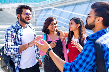 indian friends sitting on stairs outdoors with copybooksの写真素材
