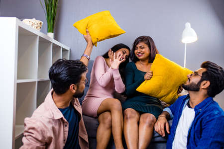 four indian friends fighting pillows at homeの写真素材