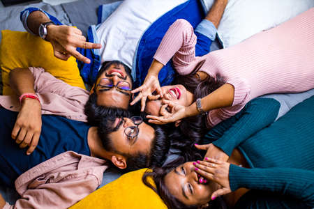 four indian friends lying down on the floor with pillowsの写真素材