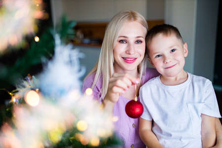 Child and mother decorating Christmas tree at homeの写真素材