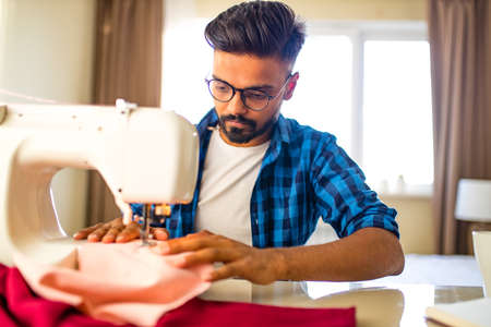 arabian man designer sewing clothes on sewing machineの写真素材