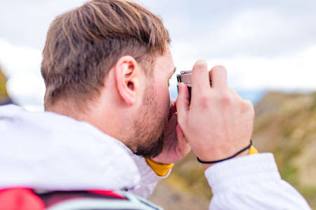 Young cheerful man photographer taking photographs with old school vintage camera in a mountainsの写真素材