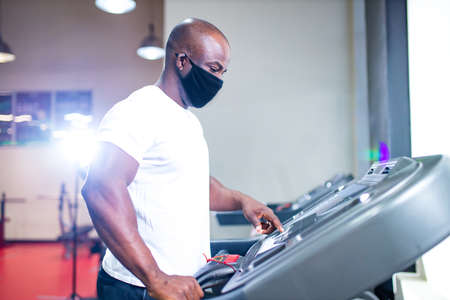 spain man in white cotton t-thirt wearing mask while working out in gym
