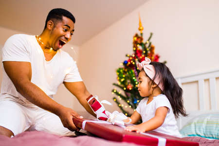 mixed race family spending holiday in the bed in bedroom christmas morning