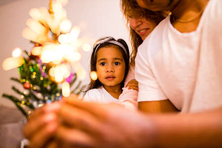 happy mixed race father and cheerful beautiful daughter decorating interior in livingroomの写真素材