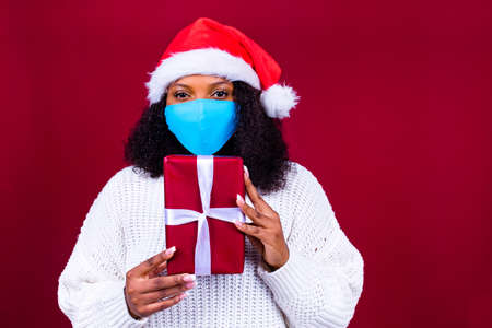 latino joyful pretty woman in medical mask and red santa claus hat laughing isolated on red background she is happy and excited full of funの写真素材