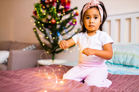 mixed race little cute girl awake in the xmas morning in bedroom and wishing a wish