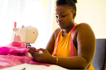 mixed race woman seamstress sews clothes in the houseの写真素材