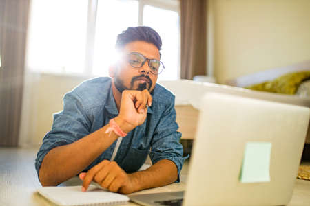 indian man training education and freelance work in new apartmentの写真素材