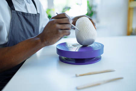 Portrait of positive latin hispanic brazilian man making ceramic pot on pottery wheel