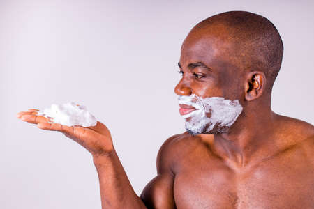 latin hispanic man with razor and shaving foam on his face studio white isolate backgroundの写真素材
