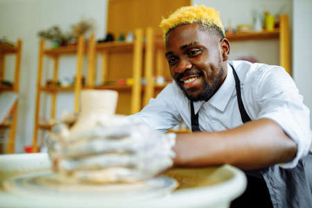 mixed race man making a vase in pottery studio