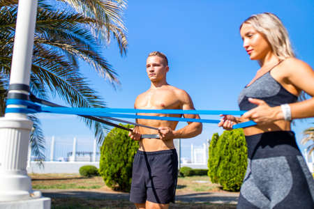 Young couple in sports outfit doing morning workout outdoors in hot summer