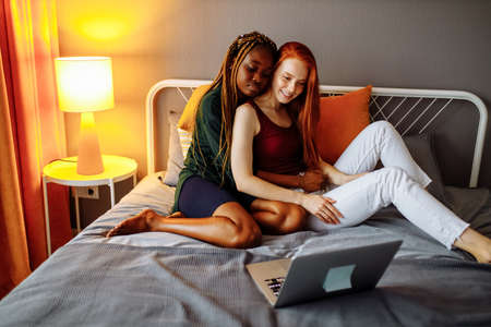 Multiracial couple girlfriends in love embracing in roomの写真素材