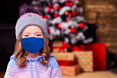Beautiful little girl in the winter warm hat and scarf and medical mask stylish fashion child look in winter new year timeの写真素材