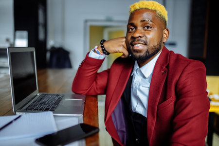 african american person sitting at office typing message note on phone near laptopの写真素材