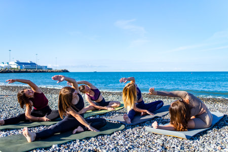 group of five women practicing yoga assans in morning beach . only girls sessionの写真素材