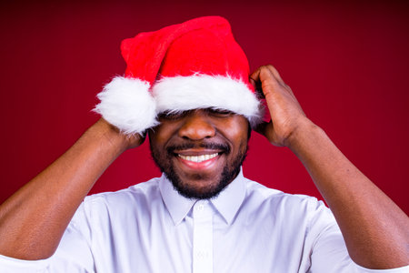 brazilian man wear santa claus headwear isolated over red color backgroundの写真素材