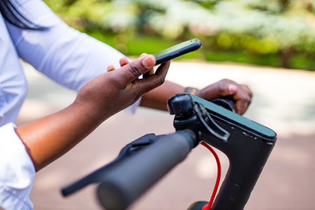 afro american woman activate and prepay a rental e-scooter or an e-bicycle on the streetの写真素材