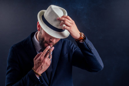 Portrait of an attractive business man with a cigar in black background studioの写真素材