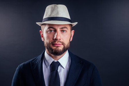 Portrait of handsome young businessman wear hat over black backgroundの写真素材