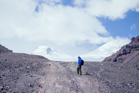 tourist climbs the mountain on the background of Elbrus