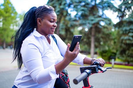afro american woman activate and prepay a rental e-scooter or an e-bicycle on the street