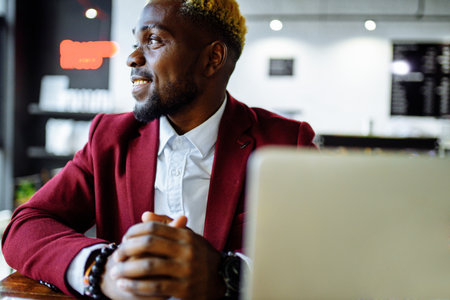 african american person sitting at office typing message note on phone near laptopの写真素材