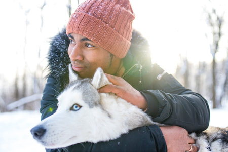 mixed race man hug his dog husky in winter forest parkの写真素材