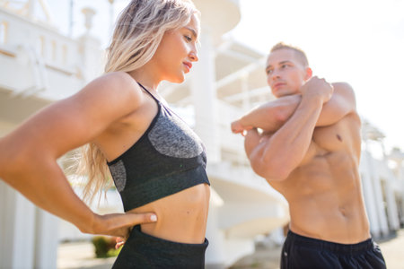 Young couple in sports outfit doing morning workout outdoors in hot summerの写真素材