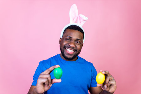 man wearing cute easter bunny ears in studio pink wall backgroundの写真素材