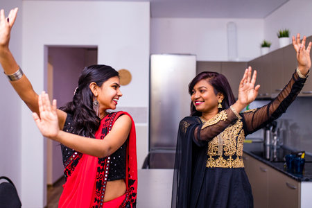 happy indian sisters are dancing together in new light apartment with design repair moving concept...