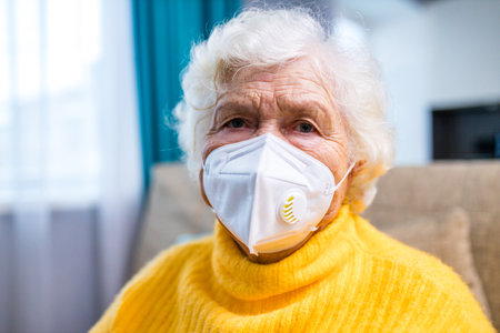 Doctor giving injection to senior woman at her house in living roomの写真素材